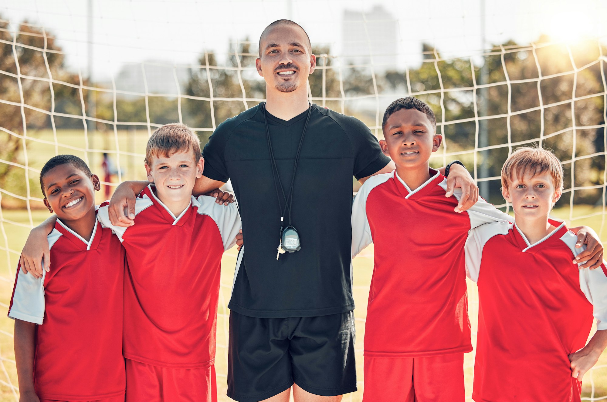 Soccer, football coach and kids team stand in goal post for team photo, before team game and teamwo